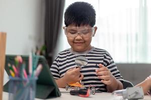 Young asia student remotely learn online at home  in coding robot car and electronic board cable in STEM, STEAM, mathematics engineer science technology computer code in robotics for kids. photo