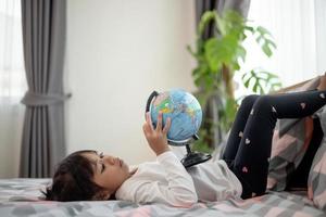 hermosa chica mirando un globo terráqueo y aprendiendo sobre geografía. foto