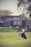 Pro golf player aiming shot with club on course.golfer on putting green about to take the shot photo