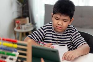 Kid self isolation using tablet for his homework,Child doing using digital tablet searching information on internet during covid 19 lock down,Home schooling,Social Distance,E-learning online education photo