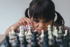 niña asiática jugando al ajedrez en casa.un juego de ajedrez foto