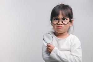 Little girl child holding a magnifying glass on white background photo