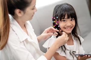 joven madre asiática atando el cabello de su hija foto