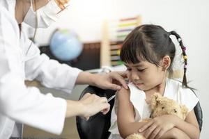 Vaccination concept. Female doctor vaccinating cute little girl in clinic photo