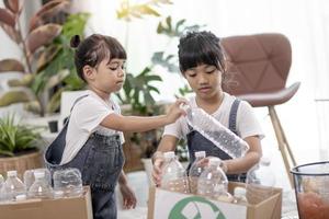 Smiling children having fun while segregating plastic bottles and paper into a bin photo