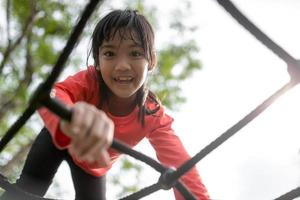 Asian little girl enjoys playing in a children playground, Outdoor portrait photo