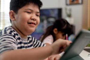 Asian boys and girls enjoy online learning by taking notes and using tablets at home. photo