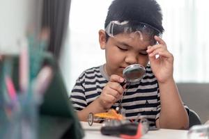 Young asia student remotely learn online at home  in coding robot car and electronic board cable in STEM, STEAM, mathematics engineer science technology computer code in robotics for kids. photo