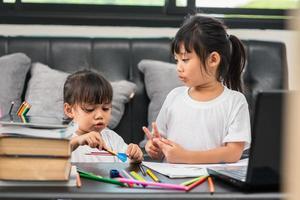 coronavirus covid-19 y aprendizaje desde el hogar, concepto de niño escolar en casa. los niños pequeños estudian en línea aprendiendo desde casa con una computadora portátil. foto