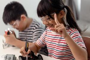 two Asian children having fun learning coding together, learning remotely at home, STEM science, homeschooling education, fun social distancing, isolation, new normal concept photo