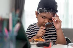 un joven estudiante de asia aprende de forma remota en línea en casa codificando un automóvil robot y un cable de placa electrónica en tallo, vapor, ingeniero matemático, ciencia, tecnología, código informático en robótica para niños. foto