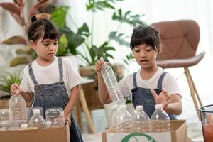 Smiling children having fun while segregating plastic bottles and paper into a bin photo