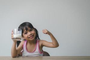 la niña asiática está bebiendo leche de un vaso, estaba muy feliz. foto