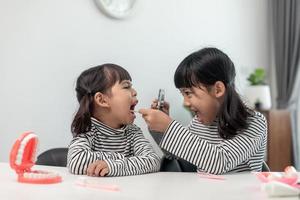 lindo niño asiático jugando con el juego de juguetes médico dentista, el niño muestra cómo limpiar y cuidar los dientes. odontología y medicina, foto