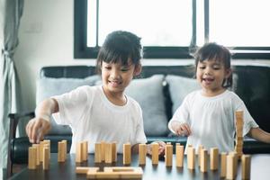 Two happy siblings playing a game with wooden blocks at home joyfully photo