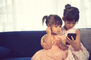 Children listening to music while sitting on a couch photo