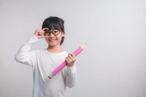 niña emocionada sosteniendo grandes lápices en sus manos. Regreso a la escuela. foto