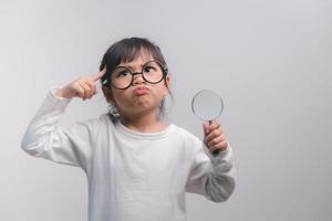 Little girl child holding a magnifying glass on white background photo