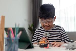 Young asia student remotely learn online at home  in coding robot car and electronic board cable in STEM, STEAM, mathematics engineer science technology computer code in robotics for kids. photo