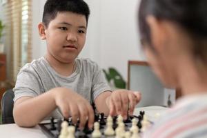 Little boy and little girl are playing chess at home.Children playing chess photo