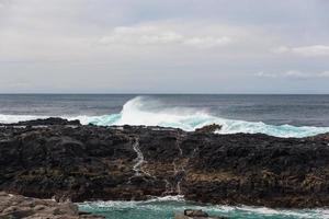 Turbulent ocean waves with white foam beat coastal stones photo