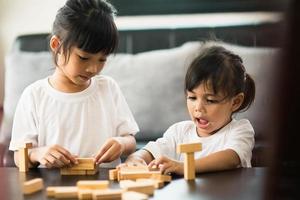 Two happy siblings playing a game with wooden blocks at home joyfully photo
