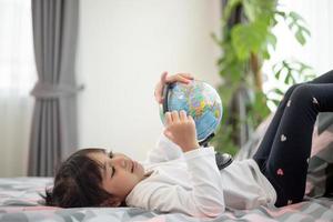 hermosa chica mirando un globo terráqueo y aprendiendo sobre geografía. foto