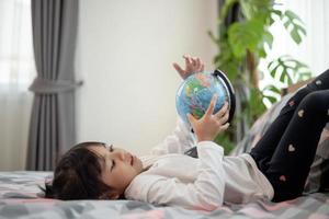 hermosa chica mirando un globo terráqueo y aprendiendo sobre geografía. foto