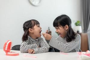 lindo niño asiático jugando con el juego de juguetes médico dentista, el niño muestra cómo limpiar y cuidar los dientes. odontología y medicina, foto