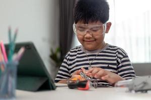 Young asia student remotely learn online at home  in coding robot car and electronic board cable in STEM, STEAM, mathematics engineer science technology computer code in robotics for kids. photo