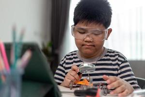 Young asia student remotely learn online at home  in coding robot car and electronic board cable in STEM, STEAM, mathematics engineer science technology computer code in robotics for kids. photo