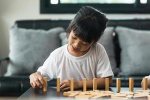 Two happy siblings playing a game with wooden blocks at home joyfully photo