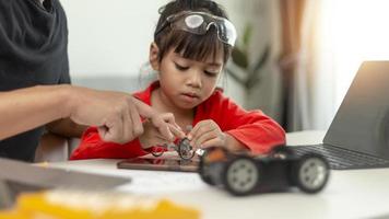 STEM education, Asian girl and father learning programming process of new robot technology. Happy family members relationship, Studying anywhere anytime to learn together at home photo