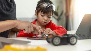 STEM education, Asian girl and father learning programming process of new robot technology. Happy family members relationship, Studying anywhere anytime to learn together at home photo