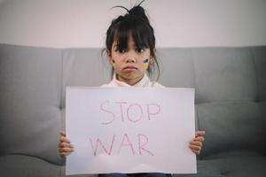 Board No war, Stop war. Little Asian girl. No war with Ukraine. Ukrainian geopolitics globe crisis. photo