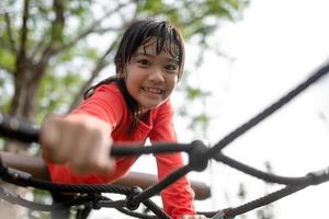 Cute little girl toddler having fun on the playground, climbing and sliding down photo