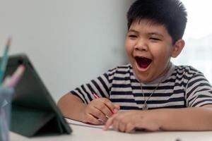 Asian child is yawning and bored while studying online at home photo