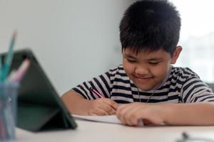 Kid self isolation using tablet for his homework,Child doing using digital tablet searching information on internet during covid 19 lock down,Home schooling,Social Distance,E-learning online education photo