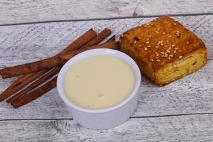 Condenced milk in the bowl with sinnamon and pastry photo