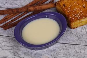 leche condensada en el bol con sinnamon y pastelería foto