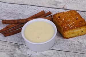 Condenced milk in the bowl with sinnamon and pastry photo