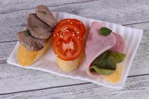 Bruschetta with tomato, ham and tongue photo