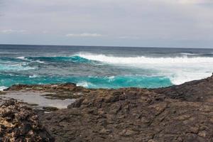 Turbulent ocean waves with white foam beat coastal stones photo