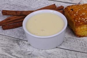 Condenced milk in the bowl with sinnamon and pastry photo