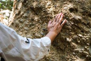 la investigadora geóloga asiática toca rocas a mano para analizar la superficie en el parque natural mae wang, tailandia. geólogo de exploración en el campo foto