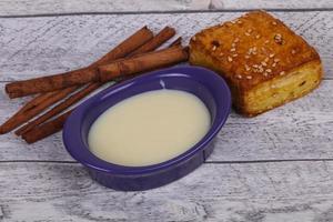 Condenced milk in the bowl with sinnamon and pastry photo