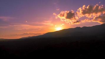 Mountain in silhouette with sunset and dramatic sky photo