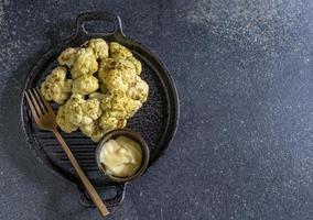 Healthy food roasted cauliflower salad in bowl dish has mayonnaise on black stone background. photo