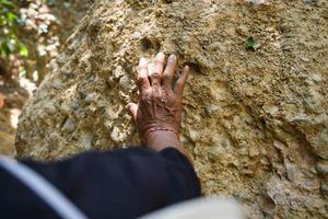 un anciano investigador geólogo asiático toca rocas con las manos para analizar superficies en el parque natural mae wang, tailandia. geólogo de exploración en el campo