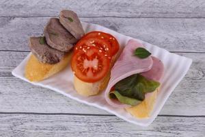 Bruschetta with tomato, ham and tongue photo